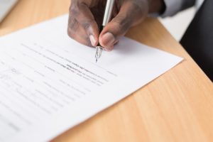 Man's hand signing a document